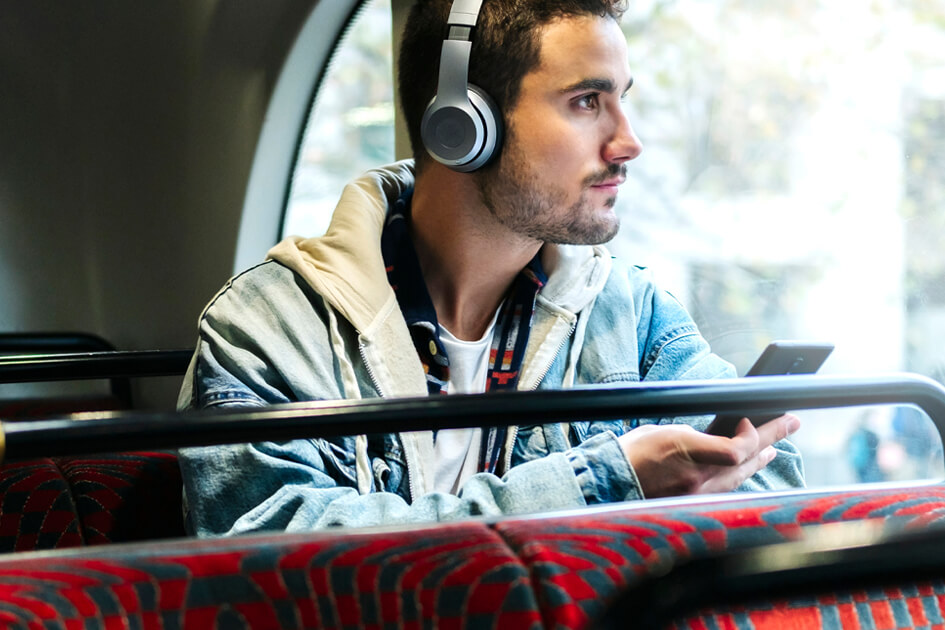 Person on bus with headphones and smartphone